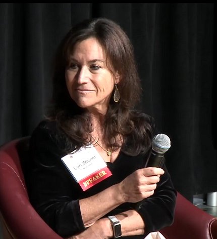 Wiener sits on stage, holding microphone.