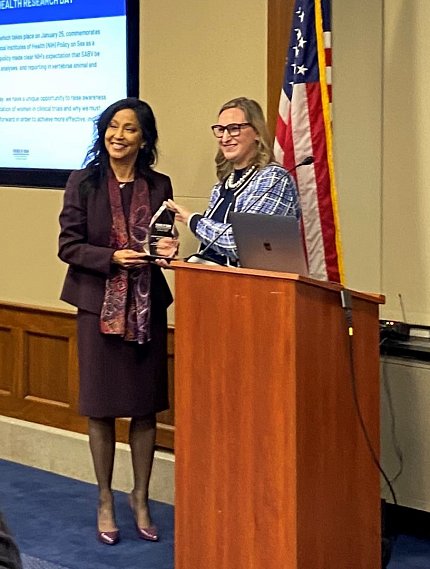 Clayton receives an award from Schubert at a podium