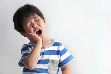 Youngster grimaces, holding his jaw