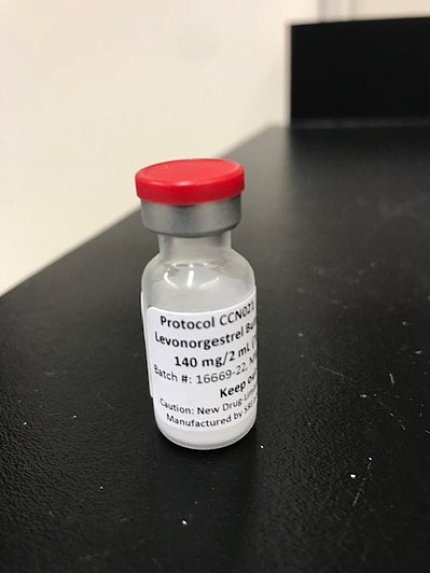 Clear bottle with red cap on black lab bench.