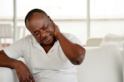Black man grimacing, holding his neck