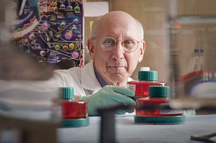 Rosenberg in gloves reaches for labeled bottle in the lab