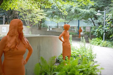 Life-sized orange statues of women grace the CC courtyard, with foliage all around.