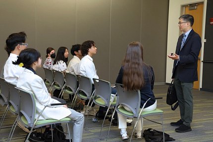 Chiang speaks facing two rows of seated students
