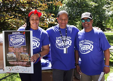 Three Camp Fantastic supporters pose with a poster advertising the BBQ.