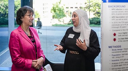 Two women chat. One wears a traditional head covering.
