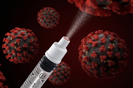 A syringe sprays droplets onto a dark screen; cells infected by Covid-19 hang in the background.