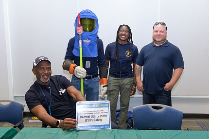 A group from the utility plant pose by table with one wearing face shield.