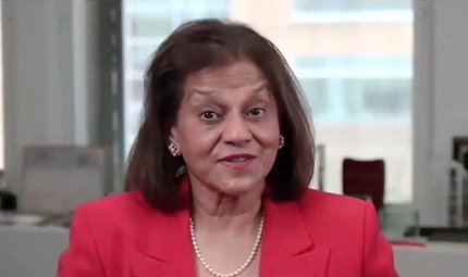 D'Souza addresses her virtual audience from an office setting.