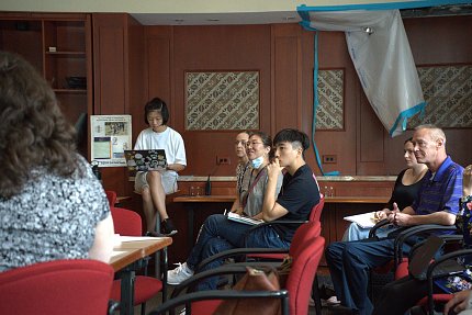 A group of students and their mentors listen and take notes from an off-camera speaker.