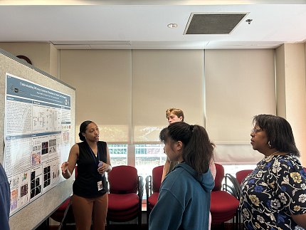 Chubb explains her research poster to a small group of onlookers