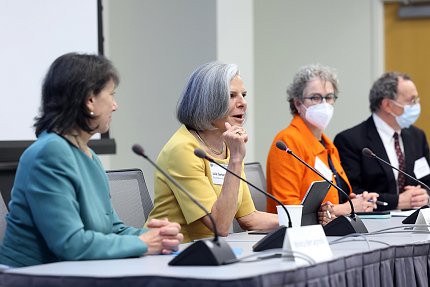 The panel of speakers sit along a gray table