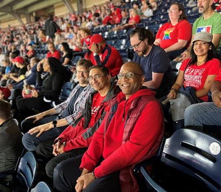 CIT employees (most wearing red shirts) seated in a stadium.