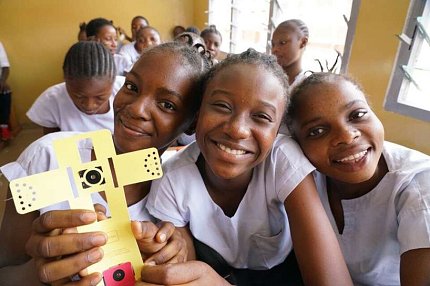 School children hold up a Foldscope