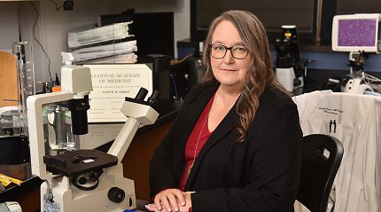 James sits next to a microscope.