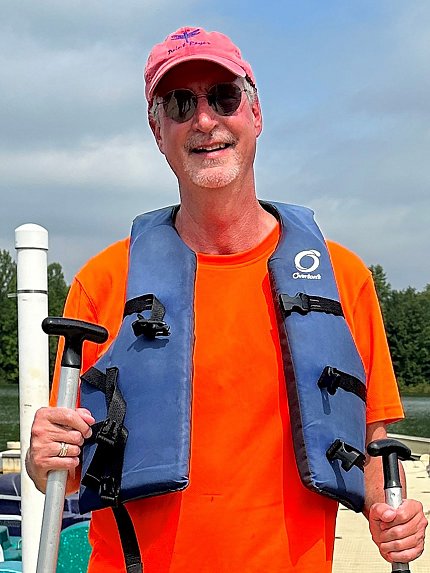 James Gnadt smiling in life vest, holding canoe paddles