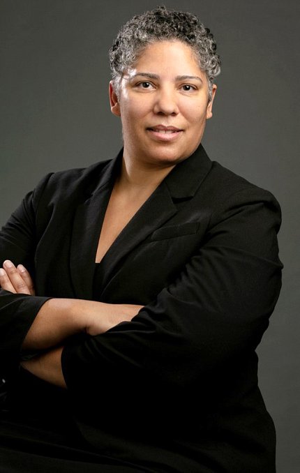 Manly head &amp; shoulders. black woman, arms crossed, smiles into camera