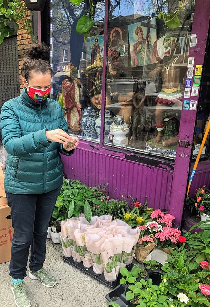 Vandebroek, wearing a red face mask and turquoise jacket, examines a small object in her left hand.