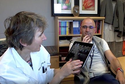 Bielekova holds up her tablet and gestures toward it, as Kosa looks on.