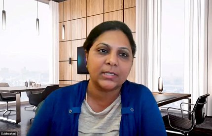 screenshot of woman in blue sweater looking into computer screen 