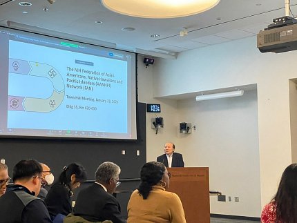 Dr. Liang addresses the audience from a podium at the front of the room