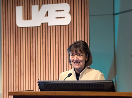 Bertagnolli smiling at podium with UAB logo backdrop