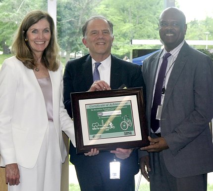 ORS Director Colleen McGowan and NIH DDM Dr. Alfred Johnson stand with colleague holding award outside on NIH's main campus.
