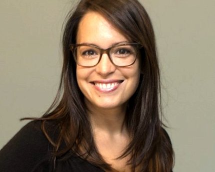 Headshot of a smiling Alter. She has brown hair and wears a dark shirt and glasses.