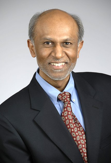 In suit &amp; tie, Nath smiles into camera in formal portrait