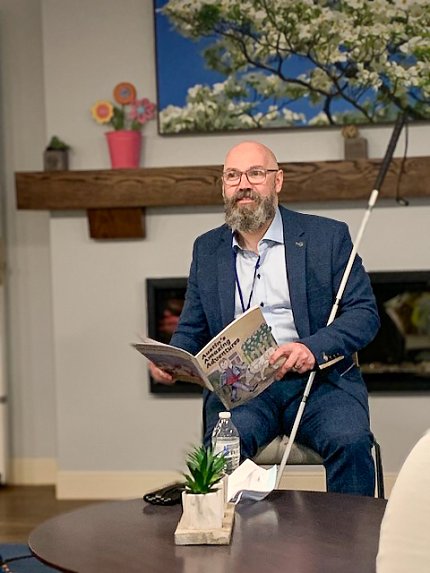 Steele sits in a chair and reads a book