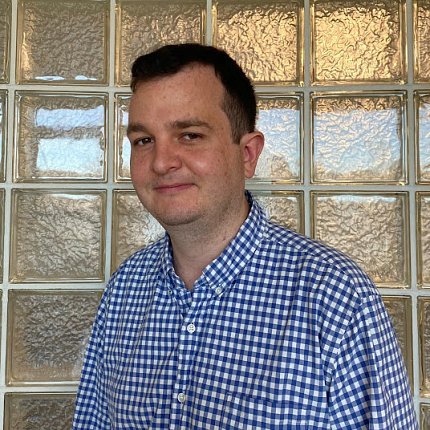 Norman in button-down shirt in front of glass wall