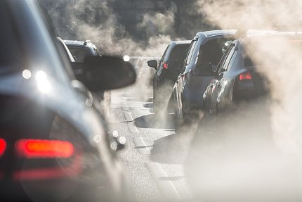 Exhaust billows from rows of automobiles in a traffic jam.