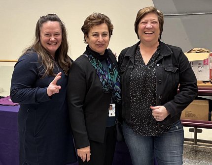 Three women pose together, smiling