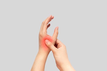 Pair of hands: the right hand massages between the left thumb and forefinger. The painful area is marked with red to signify inflammation.