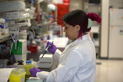 An intern holds a pipette in a lab