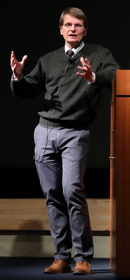 Pamer stands at podium describing his research