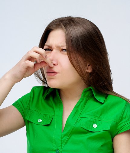 A young woman holding her nose because of an odor.