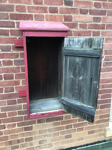 A red wooden rectangular box attached to a brick wall