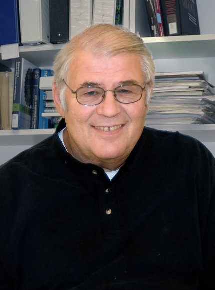 A smiling Evans in front of bookshelf in his office