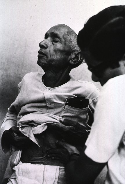 A black &amp; white photo of an older African American man getting examined by a nurse.