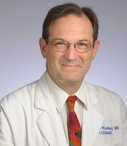 Holland smiling, in white lab coat and tie