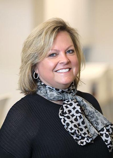 A headshot of Sofranko, a blond woman wearing a black sweater and black-and-white patterned scarf.