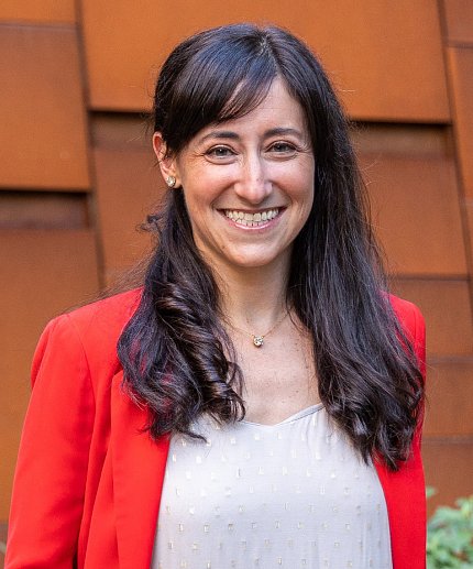 Headshot of Gabriel, smiling, wearing red cardigan