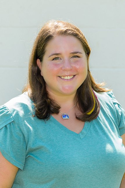 Connolly, wearing teal scrubs and posing against a white wall.