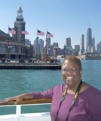 Garnett smiling, resting arm on railing, by the waterfront in Chicago