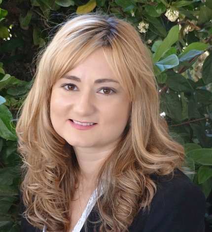 Headshot of Bartley smiling against a green leafy background.