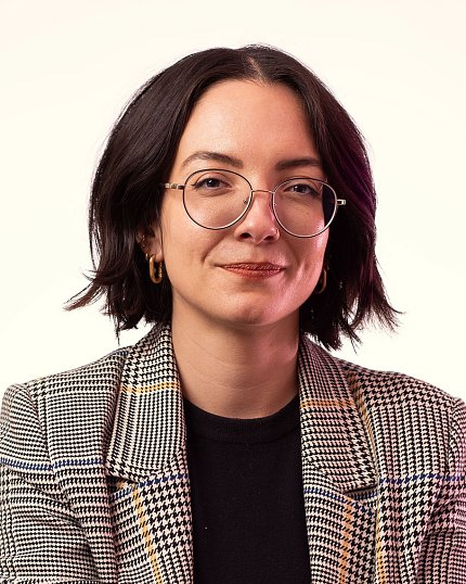 Batti, wearing glasses and a plaid jacket, silhouetted against a white background.