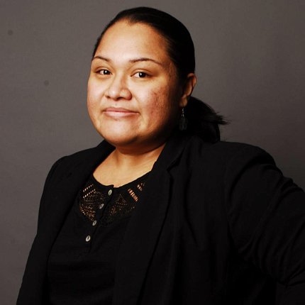 Headshot of Solomona-Faiai, wearing a black top and jacket.