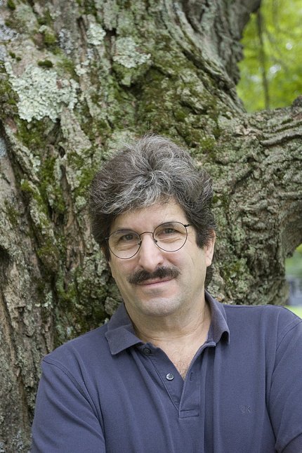 Ruvkun stands against a mossy tree trunk.