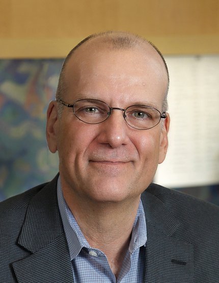 Headshot of Baxevanis, wearing glasses and a suit, against a light-colored wall.